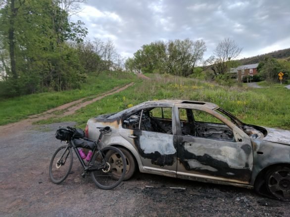 A burnt out car welcomes you to the Abandoned Turnpike.